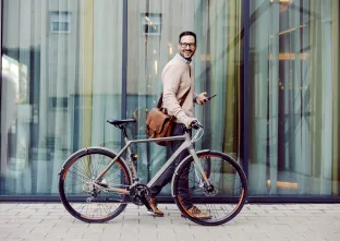 un homme souriant marche à côté de son vélo